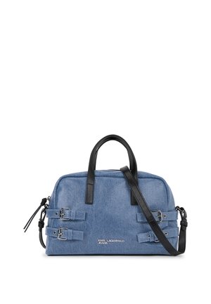 Sac en denim avec des accents en cuir noir, comportant deux sangles latérales, des poignées arrondies et une bandoulière ajustable. Détail de logo argenté.