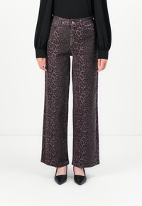 Väljadebyxor i ett lila och svart leopardmönster, med framfickor, knappstängning och en mjuk tygstruktur.