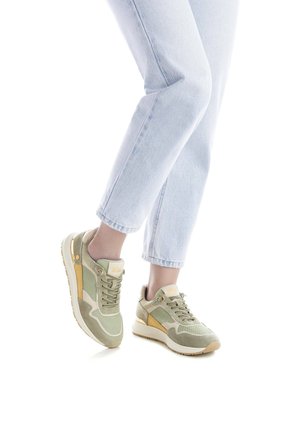 Zapatillas de ante verde y malla con detalles beige, puntera redonda, suela plana y diseño con cordones, combinadas con vaqueros cortos azul claro.