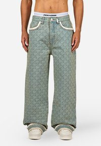 Svijetloplave traperice s uzorkom zeca, širokog kroja, srednjeg struka, kontrastnim šavovima i bijelim pojasom s logom "PEGADOR".