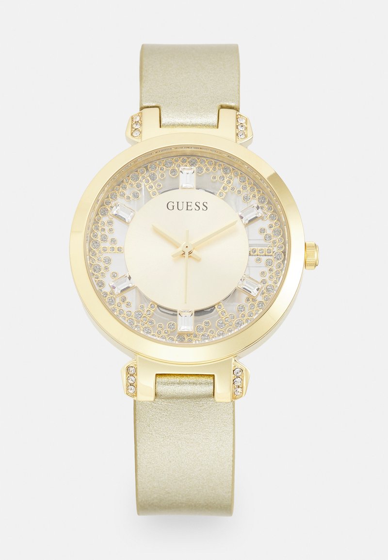 Goldfarbene Uhr mit rundem Gehäuse, beigem Glitzerdial und grünem Metallic-Armband. Mit Kristallakzenten auf der Lünette und den Stundenmarkierungen.