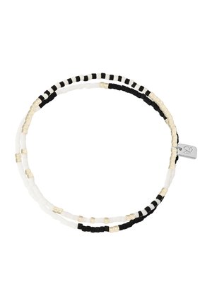 Bracelet double rangée de perles noires, blanches et dorées avec un petit charme en argent représentant un cœur et une feuille.