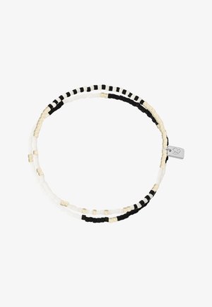 Bracelet double rangée de perles noires, blanches et dorées avec un petit charme en argent représentant un cœur et une feuille.