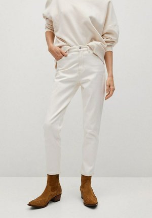 Pantaloni in denim bianco con vita alta, vestibilità slim e tasche frontali. Abbinati a stivaletti alla caviglia in suede marrone con un design ornato.