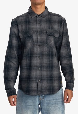 Checkered flannel shirt in shades of black and gray, featuring a button-down collar, two chest pockets, and long sleeves.