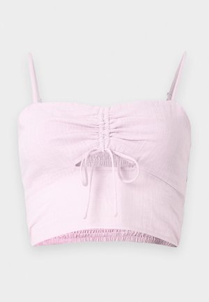 Svetloružový crop top s nastaviteľnými ramienkami, s prehnutým predným detailom a elastickým lemom. Textúrovaná látka pridáva mäkkosť.