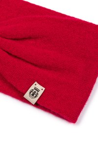 Red knitted headband with a textured pattern and a small tan label featuring a graphic design. The material appears soft and warm.