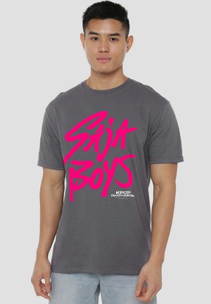 Gray cotton t-shirt with a crew neckline featuring bold pink text "Saja Boys" and "KPOP Demon Hunters" logo at the bottom. Short sleeves.