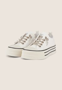 Sneaker platform bianche con tessuto testurizzato, lacci metallici e un dettaglio a striscia nera sulla suola. Presentano un occhiello sul tallone.
