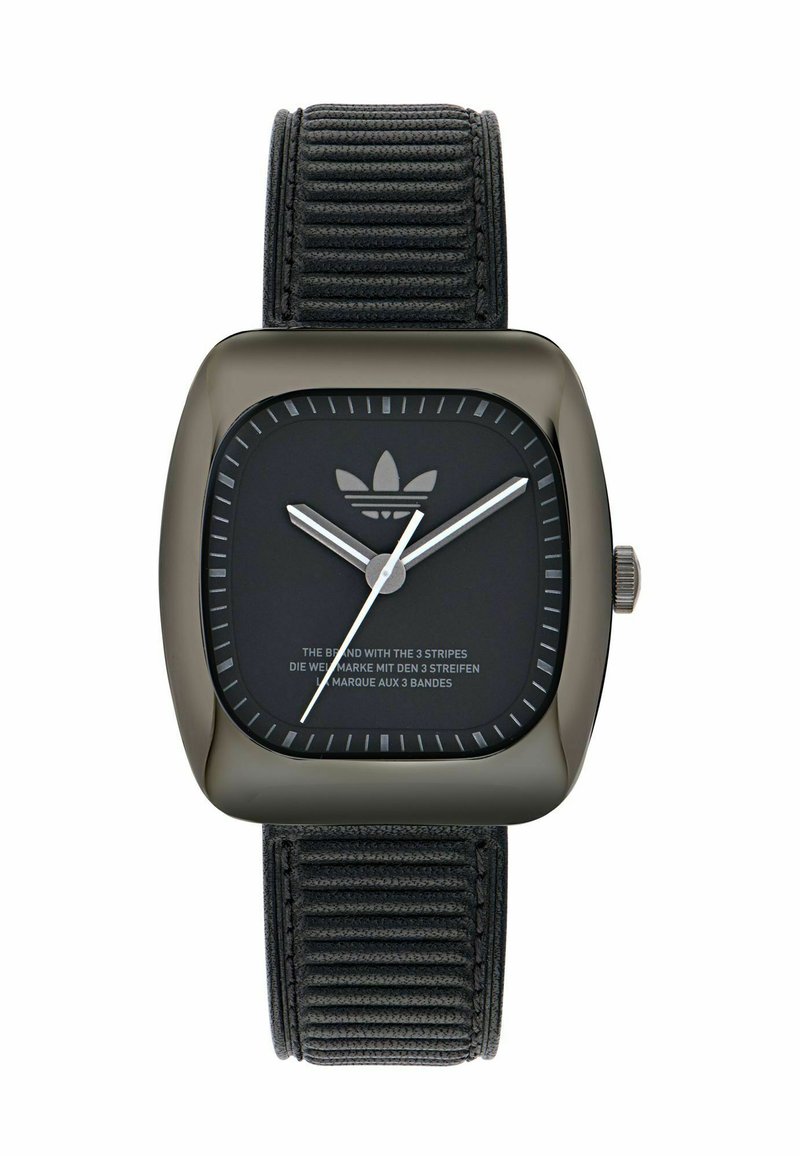 Montre carrée noire avec finition mate, aiguilles argentées, bracelet en tissu noir à rainures, et un logo en contour en haut du cadran.