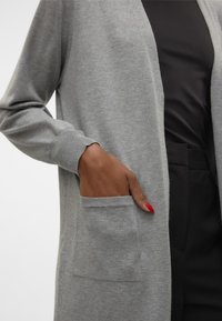 Long, open-front cardigan made from soft gray material, featuring ribbed cuffs and a front pocket for added functionality.
