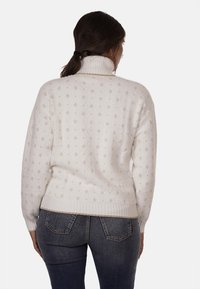 Maglione bianco con collo alto, caratterizzato da una superficie testurizzata e un delicato motivo a diamante. Polsini e orlo inferiore a costine.