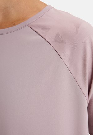 Close-up van een lichtpaarse shirt met een subtiel geometrisch patroon op de schouderstof.