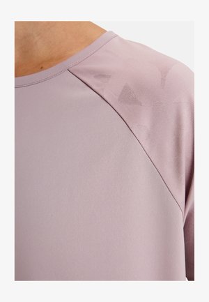 Gros plan sur une chemise lavande avec un motif géométrique texturé subtilement sur le tissu de l'épaule.