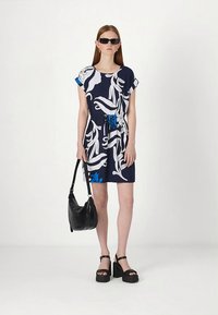 Temno modra obleka z belim cvetličnim vzorcem, ožana v pasu, s kratkimi rokavi. Kombinirana s črnimi sandali platformami in črno torbico čez ramo.