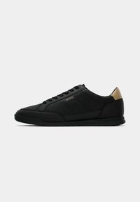 Baskets basses noires avec lacets à l'avant, semelle texturée, accent doré au talon et logo BOSS sur le panneau latéral.