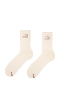 Jasnobeżowe skarpety w prążki z motywem słońca i fal w kolorze brązowym, z małą etykietą marki na kostce.