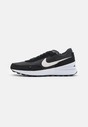 Black leather and suede sneaker with a white Nike swoosh, featuring a layered sole with black rubber tread and perforated toe details.