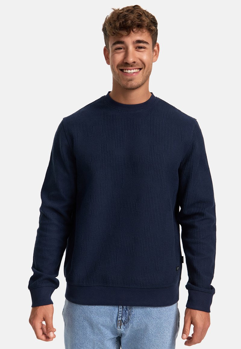 Sudadera texturizada azul marino con cuello redondo, puños y dobladillo acanalados. Presenta un patrón sutil para un interés visual añadido.