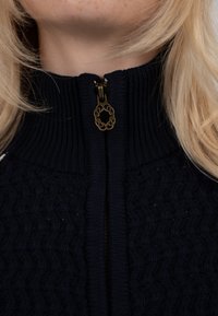 Pull en maille bleu marine avec col côtelé et fermeture éclair ornée d'un accent décoratif en métal doré au niveau de la glissière. Motif texturé sur le tissu.
