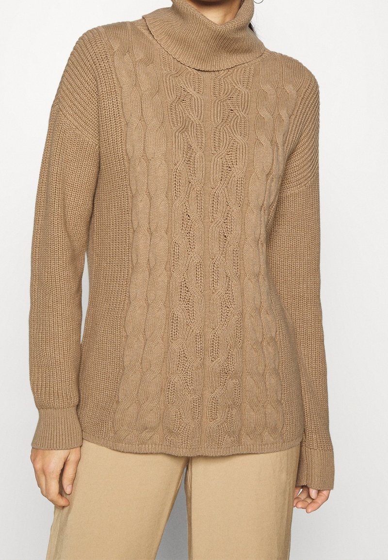 Beige gebreide trui met een omgeslagen col, voorzien van een getextureerd kabelpatroon in het midden en geribde manchetten. Glad, zacht materiaal.
