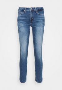 Jeans ajustados de mezclilla azul desgastados con botón frontal y cremallera, cinco bolsillos y logo de la marca sutil en el pequeño bolsillo derecho.