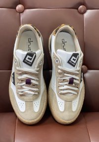 Sneakers bianchi e beige realizzati in pelle e suede, con suola beige texture, lacci a strisce marroni e tallone con stampa leopardata.