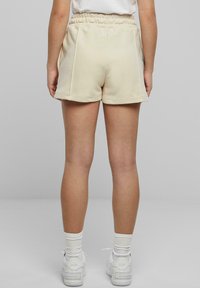 Mjuka, krämfärgade shorts med elastisk midjeband, sidfickor och avslappnad passform, ihop med vita sneakers och ribbade strumpor.