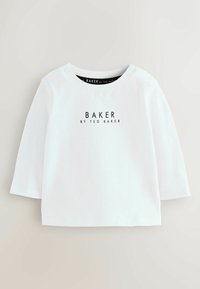 Camicia lunga bianca in cotone con collo tondo, dotata di bottoni a pressione su una spalla e un logo stampato in nero sul davanti.