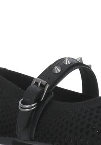 Sandalo nero con tomaia in rete, cinturino in pelle con borchie argentate e chiusura a fibbia. Materiale texturizzato con una suola robusta.