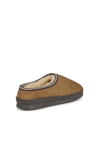 Bruine suède slipper met een zachte, tan vachtvoering. Heeft een gestructureerde grijze rubbere zool en contrasterende witte stiksels langs de kraag.