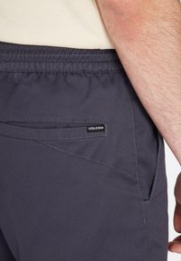 Dark gray shorts with an elastic waistband, side pocket, and a small black Volcom logo tag. Material appears smooth with a slight sheen.