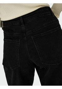 Sorte denimjeans med høj talje, der har to baglommer og subtile syninger. Stoffet virker robust og har en mat overflade.