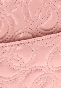 Rosa glossy læder med et quiltet bølge mønster og synlige syninger; den glatte tekstur forbedrer det visuelle udtryk.