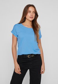 T-shirt bleu clair à manches courtes avec un col rond, fabriqué en tissu doux, associé à un pantalon noir taille haute et une ceinture noire.