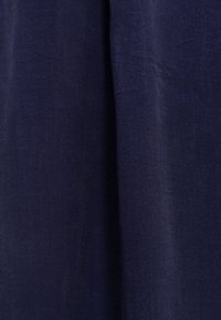 Tessuto di lino blu navy, testurizzato, con una caduta morbida, presenta una superficie liscia e sottili variazioni di tono su tutto il materiale.