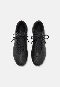 Černé fotbalové boty s texturovaným syntetickým svrškem, kulatou špičkou a plochými tkaničkami. Obsahují jemně ražené vzory a polstrovaný vnitřek.