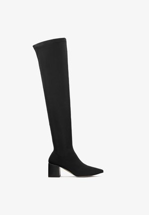 Melna augstpapēžu zābaku bikses, kas izgatavotas no elastīga materiāla, ar norādītu pirkstu un masīlu kvadrātveida papēdi ar gludu tekstūru.