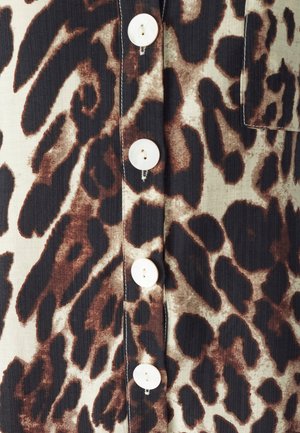 Blouse à imprimé léopard en tons beige et marron, dotée de cinq boutons blancs, d'un col à rabat et d'un tissu texturé.