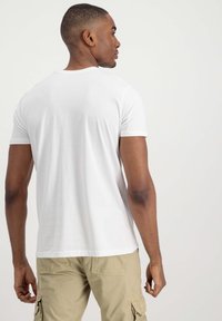 Camiseta blanca de manga corta con cuello redondo, forma ajustada y tela de algodón suave, acompañada de pantalones cortos cargo beige.