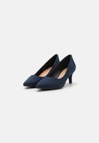 Mörkblå mocka högklackade pumps med spetsiga tår och tunna 5 cm klackar. Slät yta och minimalistisk design. Inga synliga mönster eller detaljer.