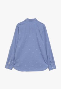 Blauw gestreepte overhemden met lange mouwen. Kenmerkt zich door kleine witte rechthoekige patronen en een afgeronde onderkant. Zachte textuur van de stof.