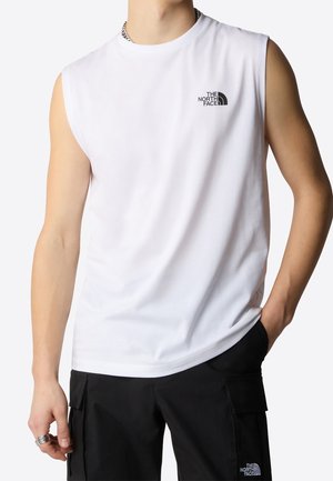 Ärmelloses weißes Hemd mit The North Face-Logo auf der Brust, getragen von einer Person mit schwarzen Cargo-Hosen, Hand in der Tasche und silbernem Ring an der linken Hand.