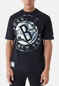 T-shirt noir en coton avec un grand motif circulaire affichant "Brooklyn" et "New York", accompagné d'un logo "B" bien en vue.