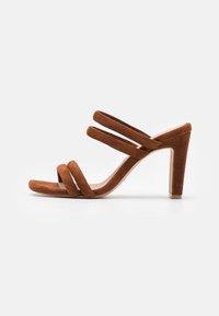 Bruine suede sandalen met hoge hakken, voorzien van drie gekruiste banden, een vierkante neus en een chunky hak voor een stabiele basis.