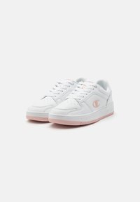 Zapatillas blancas con una parte superior sintética suave, acentos de malla, detalles rosas en la suela y un logo en el lateral. Diseño clásico con cordones.
