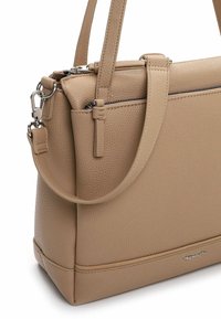 Beżowa skórzana torebka o uporządkowanym kształcie, z podwójnymi uchwytami u góry, zamkiem błyskawicznym i srebrnymi akcentami metalowymi. Teksturowana powierzchnia.