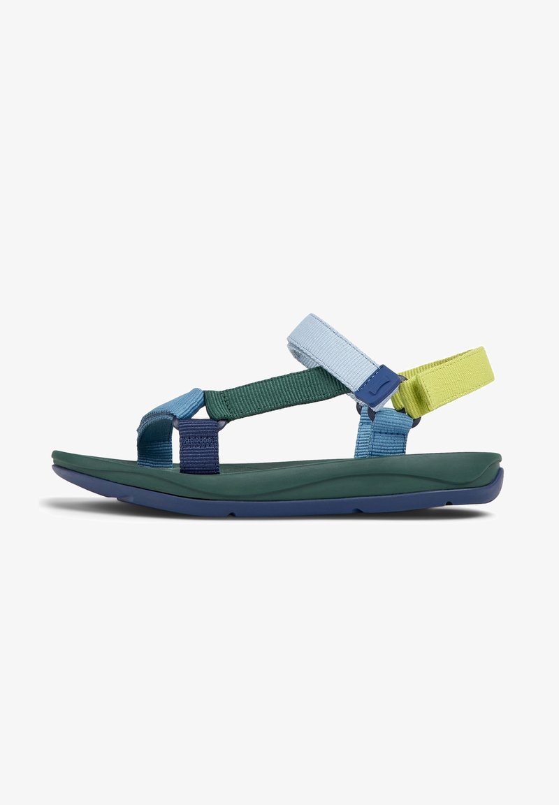 Sandales multicolores avec des sangles ajustables en bleu, vert et jaune, une semelle intérieure verte texturée et une semelle extérieure bleu marine.