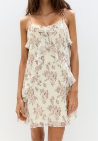 Vestido de tela ligera con estampado floral, con acentos de volantes en el escote y el dobladillo. Presenta tirantes delgados y un corte holgado.