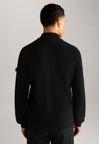 Schwarzer, gestrickter Pullover mit geripptem Muster, langen Ärmeln und hohem Kragen. Minimalistisches Design ohne sichtbare Akzente oder Verzierungen.